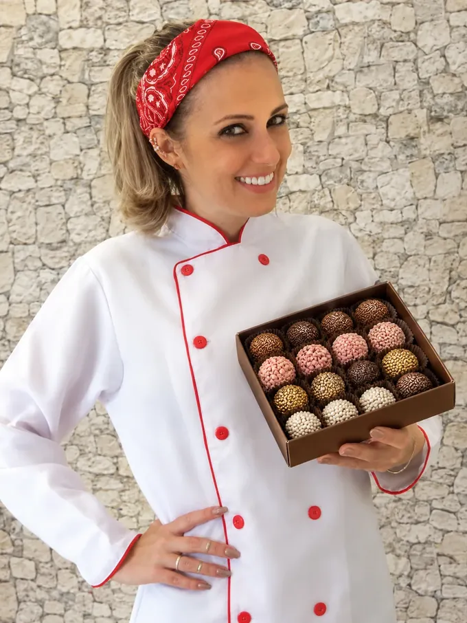 Julia, da Formiga Dondoca, sorrindo e segurando uma caixa de brigadeiros gourmet